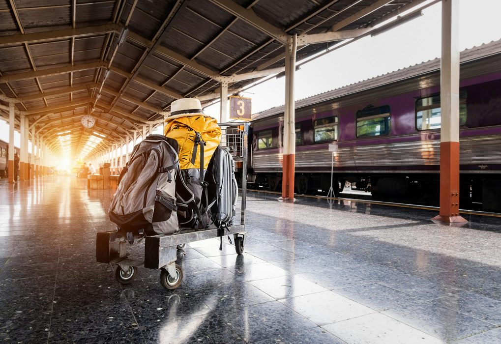 A traveler's baggage cart on an urban railway station platform at sunrise.