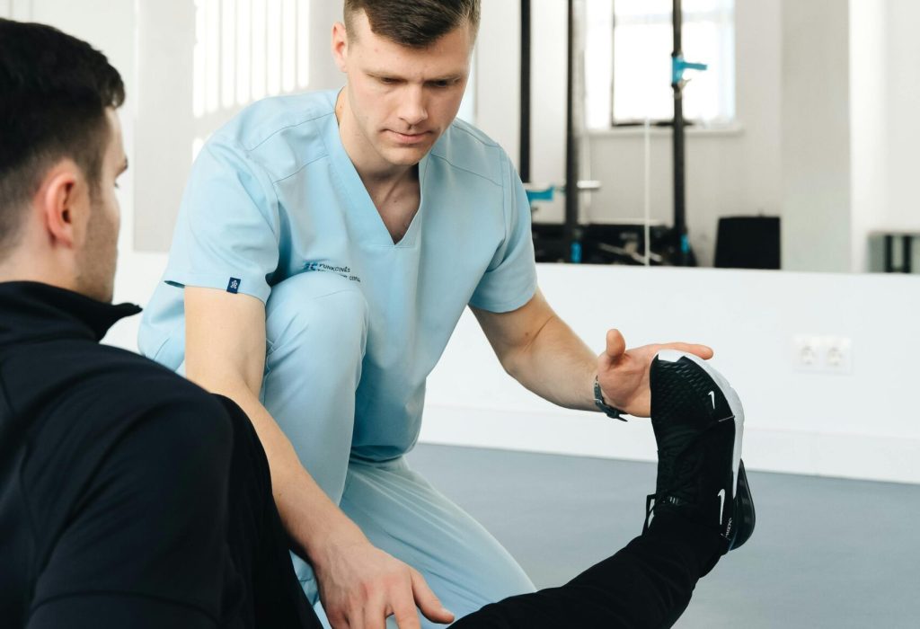 Experienced physiotherapist helps patient stretch leg in a modern clinic setting, focusing on rehabilitation.