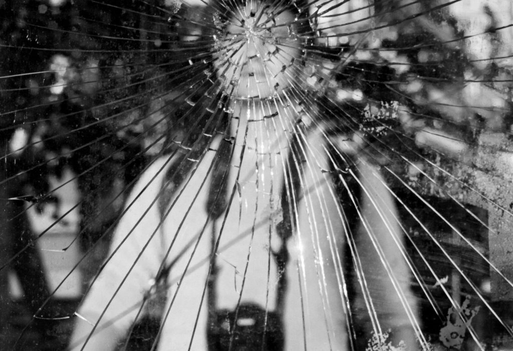 A man with a camera captured in a striking reflection through shattered glass in Buenos Aires.