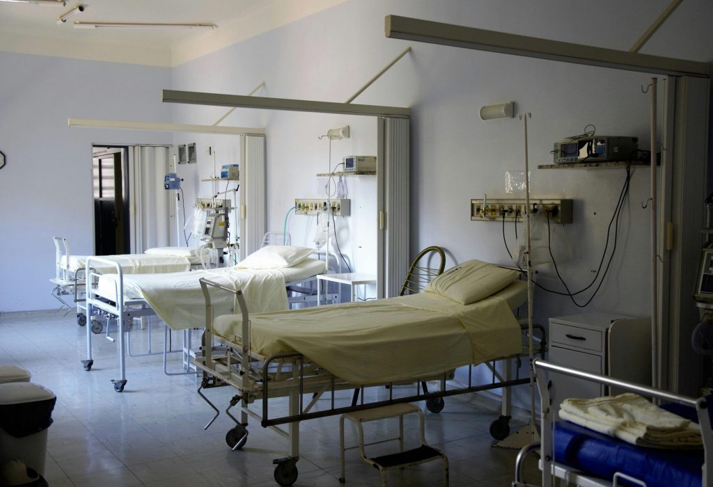 Spacious hospital room with several empty beds and medical equipment, emphasizing healthcare and hygiene.
