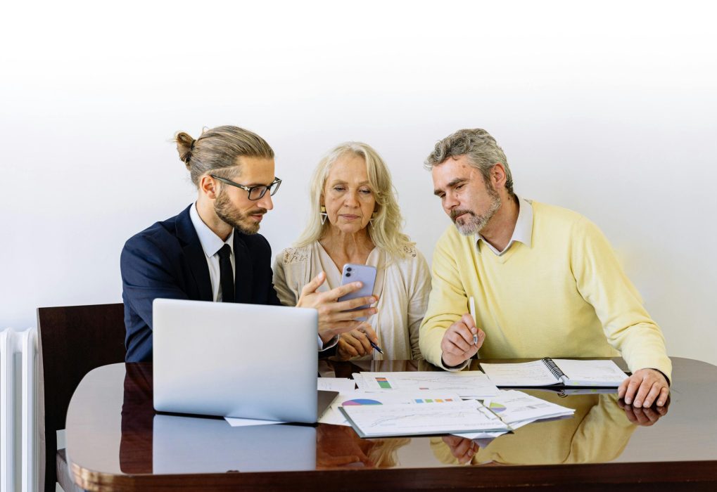 Three individuals collaborating on financial documents during a business meeting.
